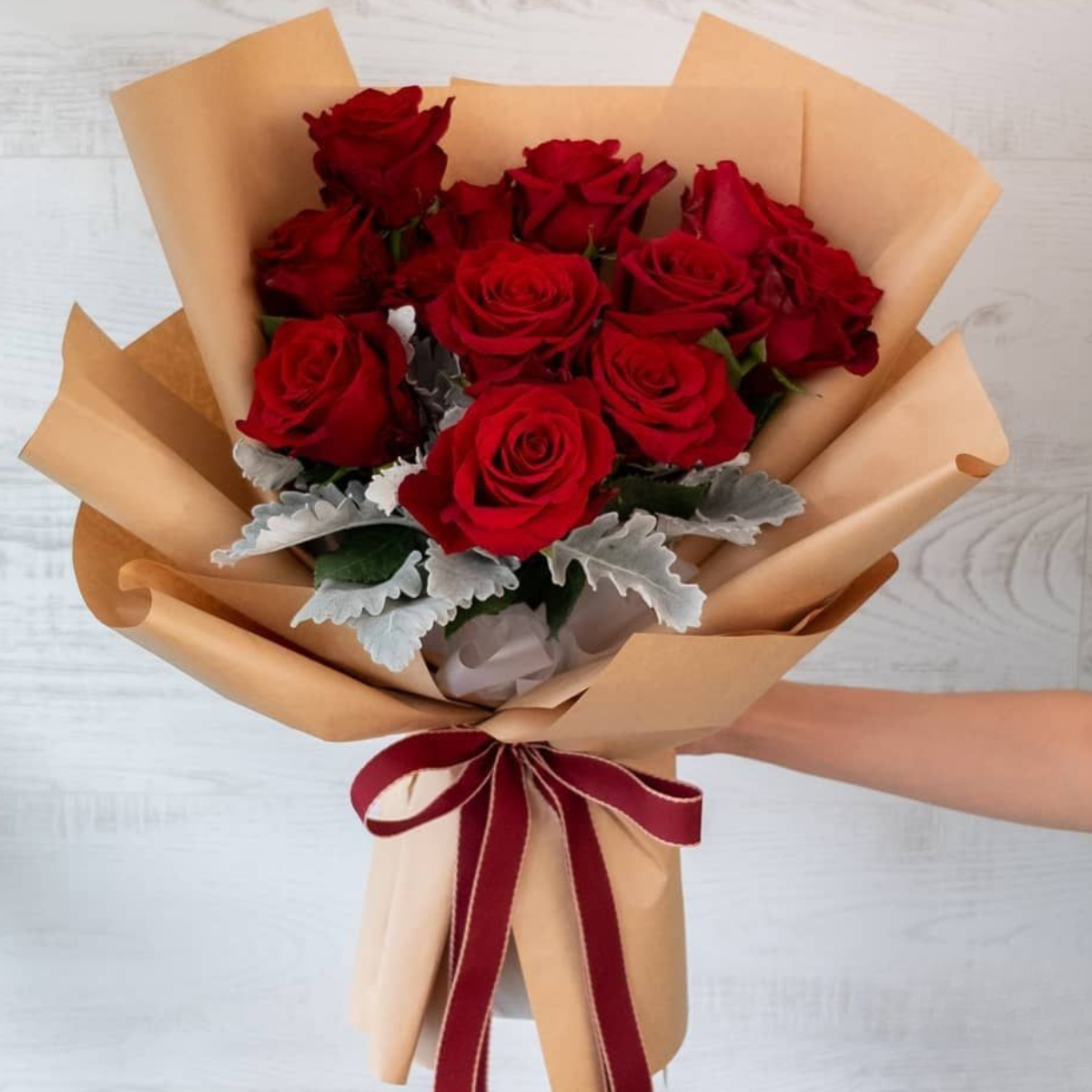 Valentine’s Bliss Bouquet of red roses with green leaves, wrapped in brown paper with a red ribbon - Petal Frost Dubai