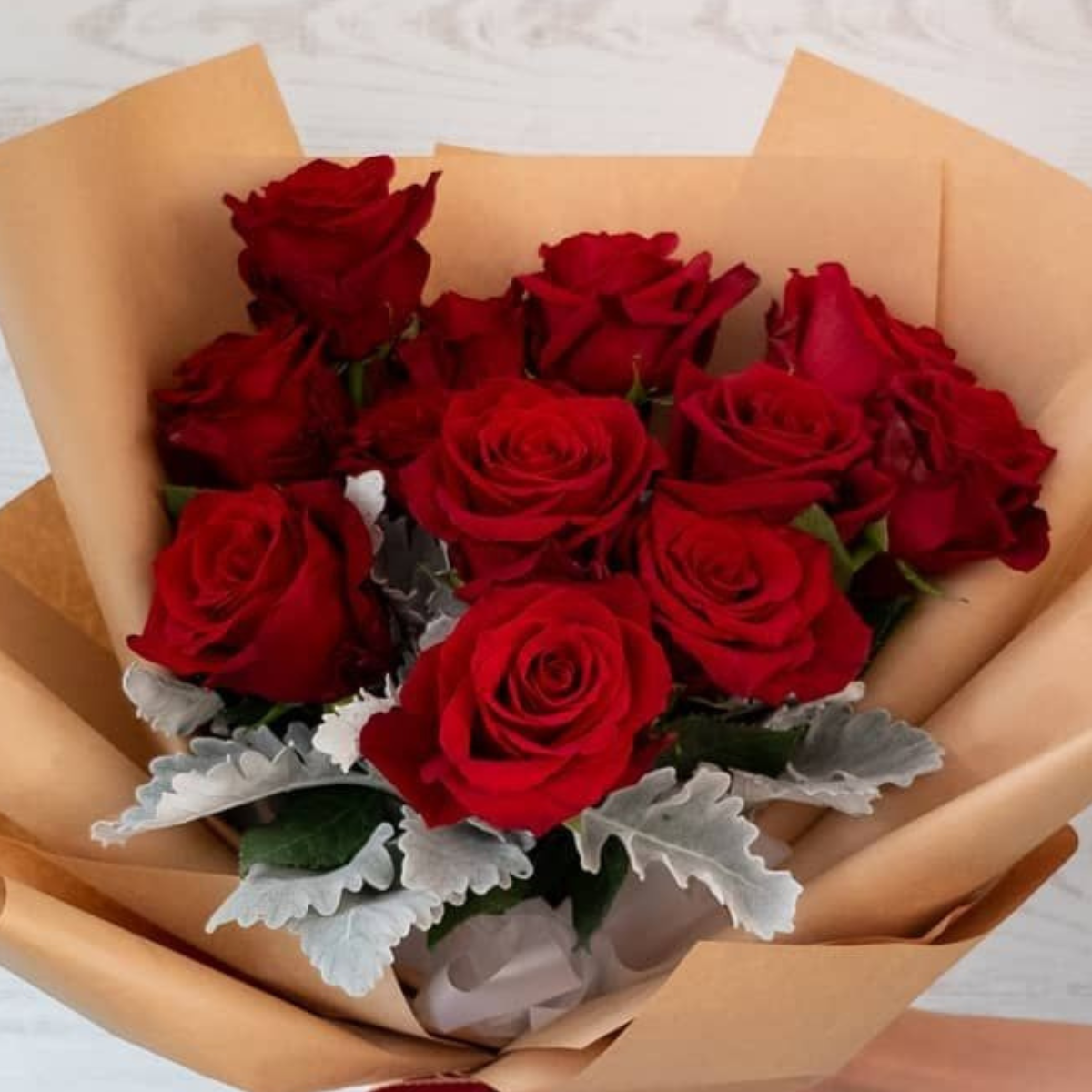 Valentine’s Bliss Bouquet of red roses with green leaves, wrapped in brown paper with a red ribbon - Petal Frost Dubai